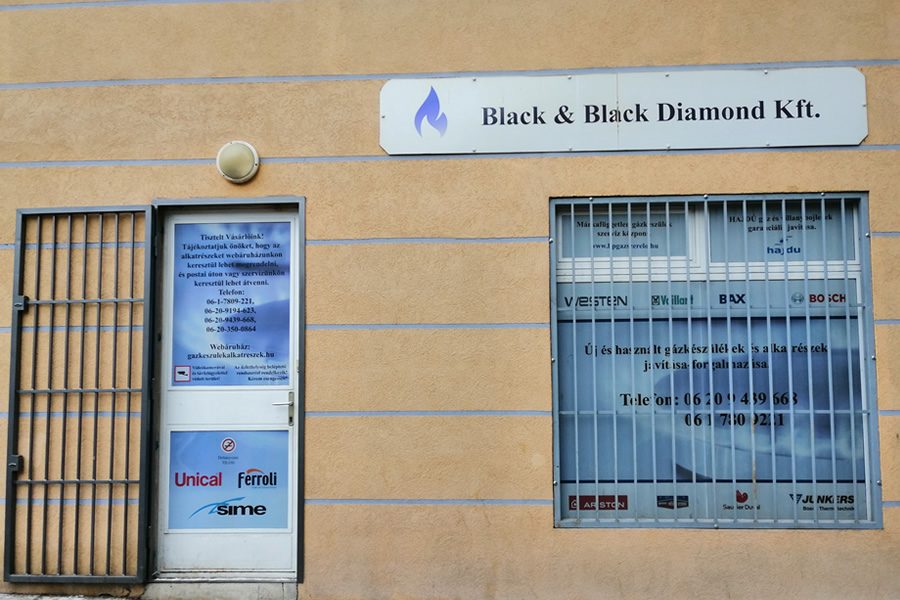 A szaküzlet bejárata és kirakata a Black & Black Diamond Kft. cégtáblájával, mellette a láng alakú céglogó